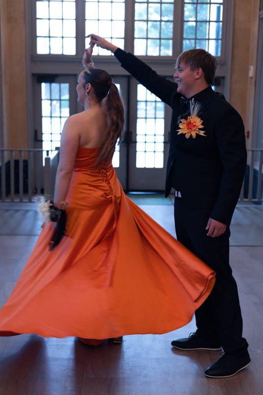 Couple dancing, her orange gown mid-twirl